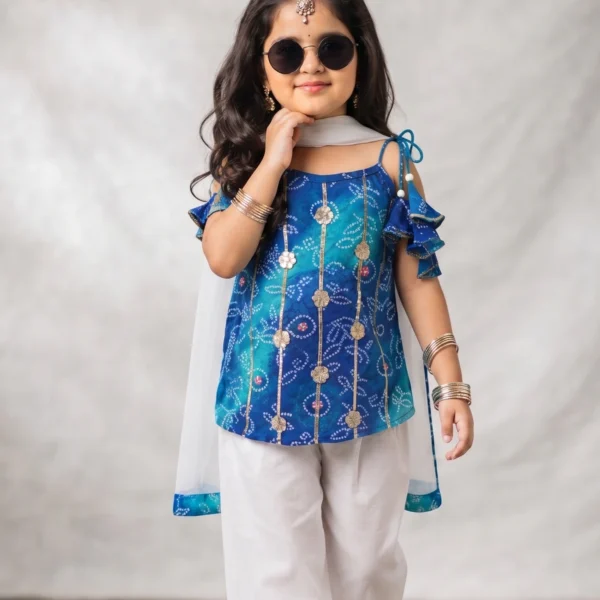 Little girl wearing a blue printed pure cotton festive kurti adorned with intricate Gota patti work, paired with white pants featuring a Gota border and a sheer matching dupatta.