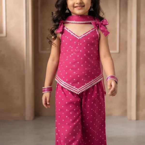 Little girl wearing a vibrant pink pure cotton Indo-Western outfit featuring an asymmetric tie-knot strap top and matching palazzo pants with delicate silver detailing.