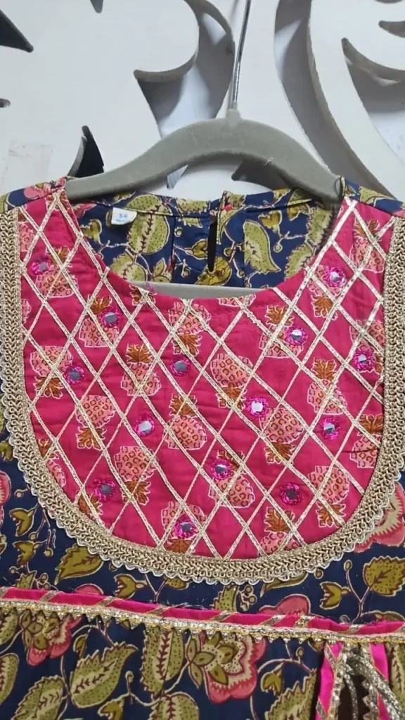 Close-up view of the pink and navy blue cotton kurti yoke featuring intricate mirror work, crisscross gold lace detailing, and embroidered borders.